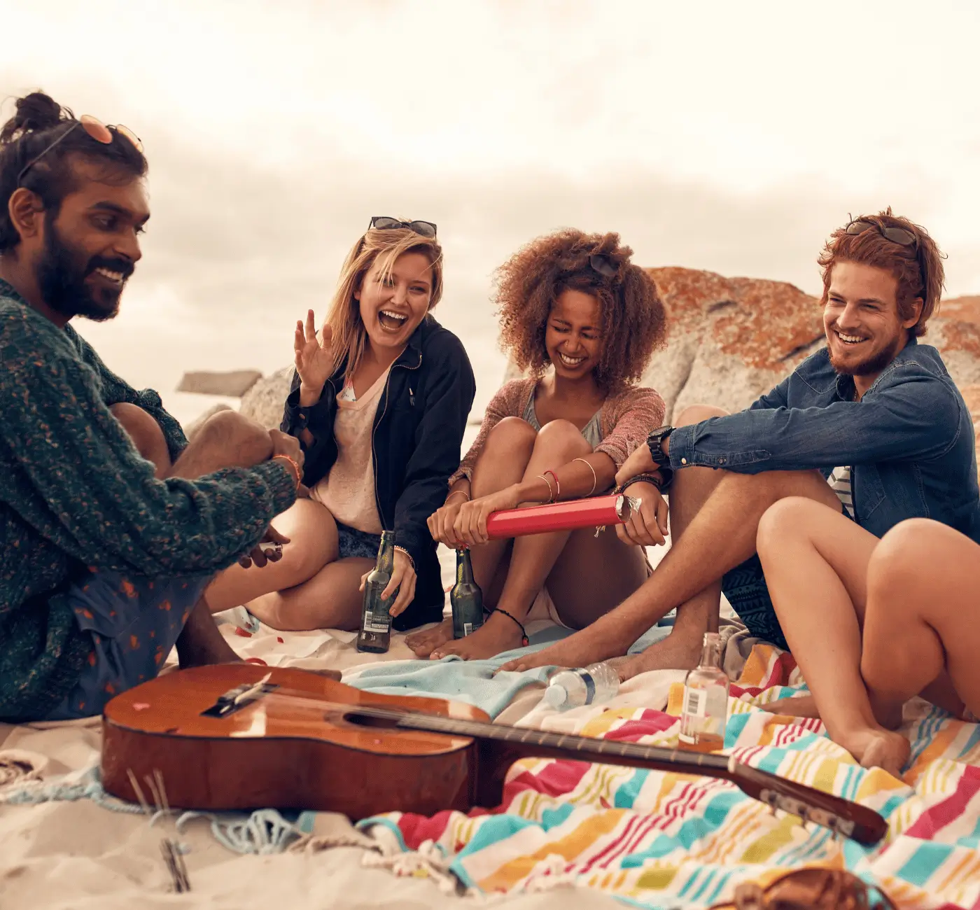 Group of friends laughing on the beach, joyful healthy living