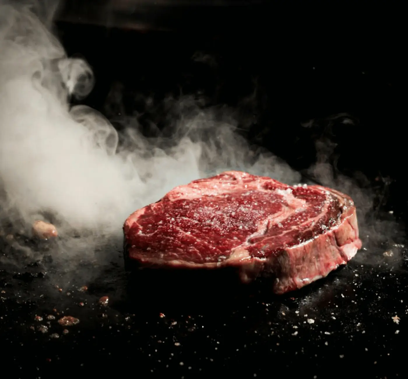 Raw ribeye steak searing on a hot skillet, high-fat carnivore nutrition